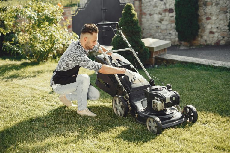 Man in summer attire using a lawnmower on a sunny day, showcasing gardening tools.