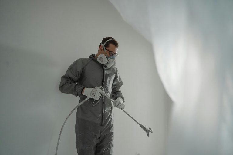 Person in protective gear painting a wall, showcasing house renovation work.